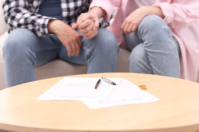 Photo of Man and woman signing marriage contract at wooden table indoors, closeup