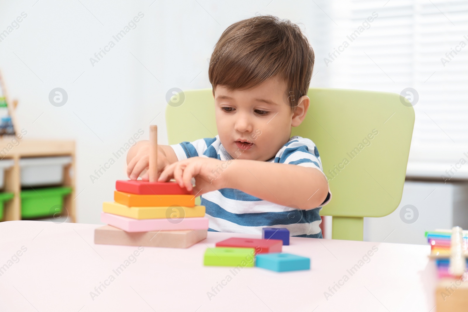 Photo of Little child playing with toy pyramid at table