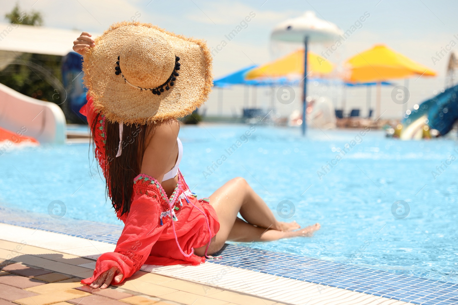 Photo of Young woman sitting near outdoor swimming pool. Space for text