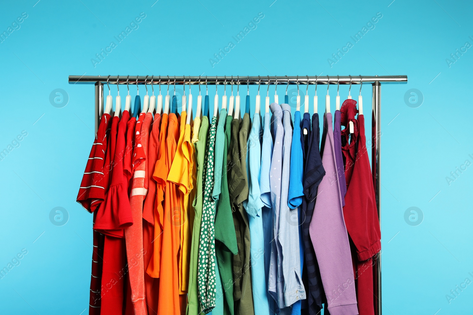 Photo of Wardrobe rack with different bright clothes on color background