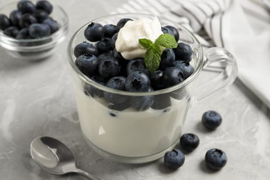 Photo of Delicious yogurt with blueberries served on grey marble table, closeup