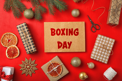 Image of Flat lay composition with gifts and text Boxing Day on red background