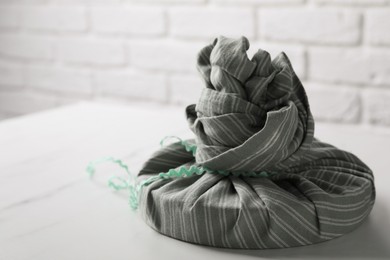 Furoshiki. Things packed in fabric on white marble table, space for text