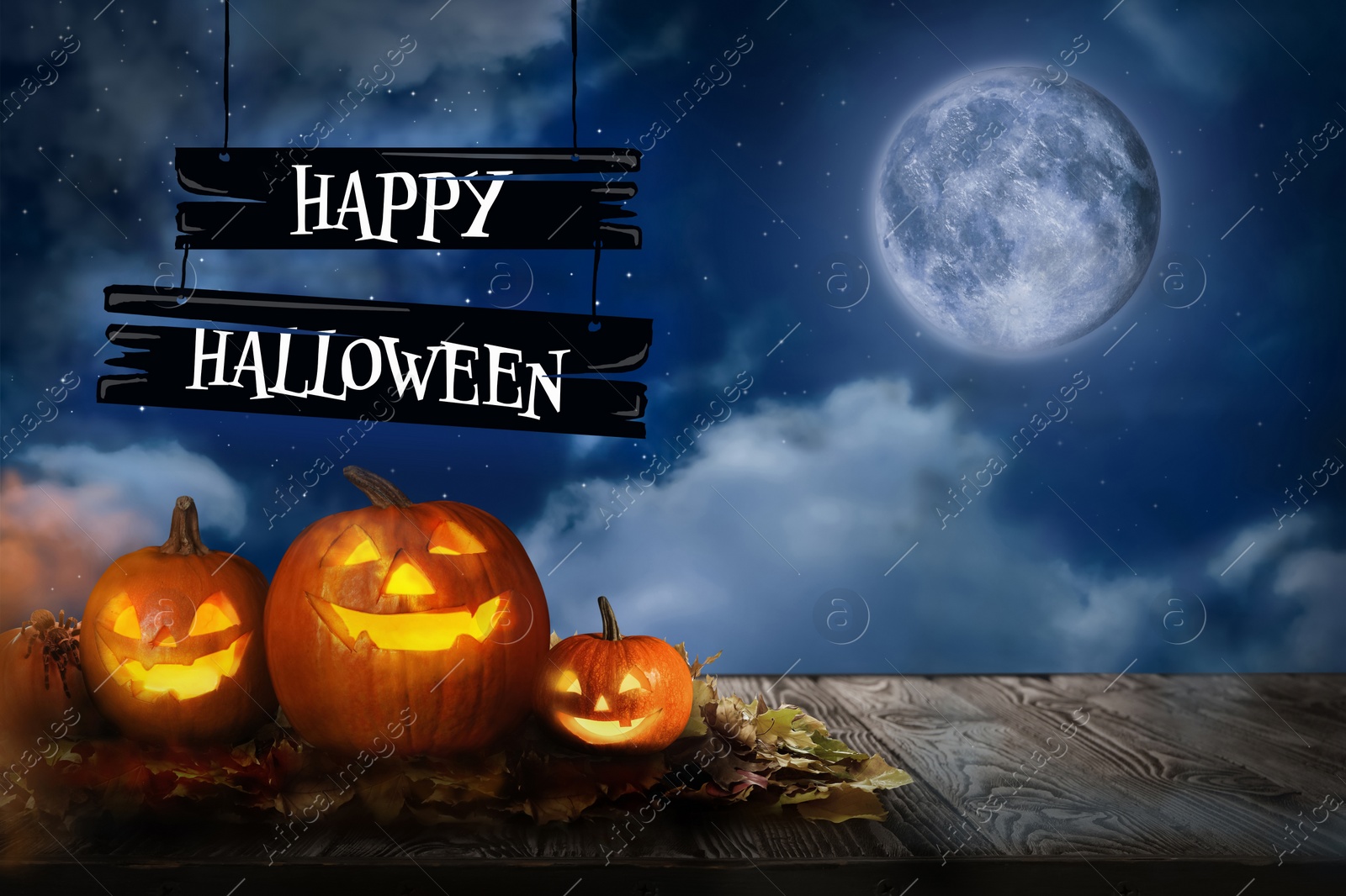 Image of Happy Halloween. Spooky pumpkin jack o'lanterns on wooden table under full moon