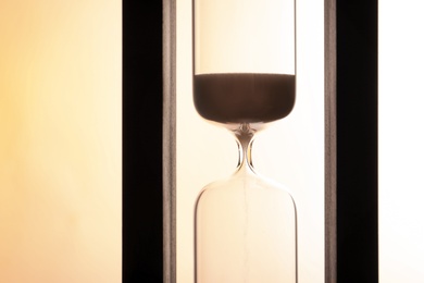 Hourglass with flowing sand on light background. Time management