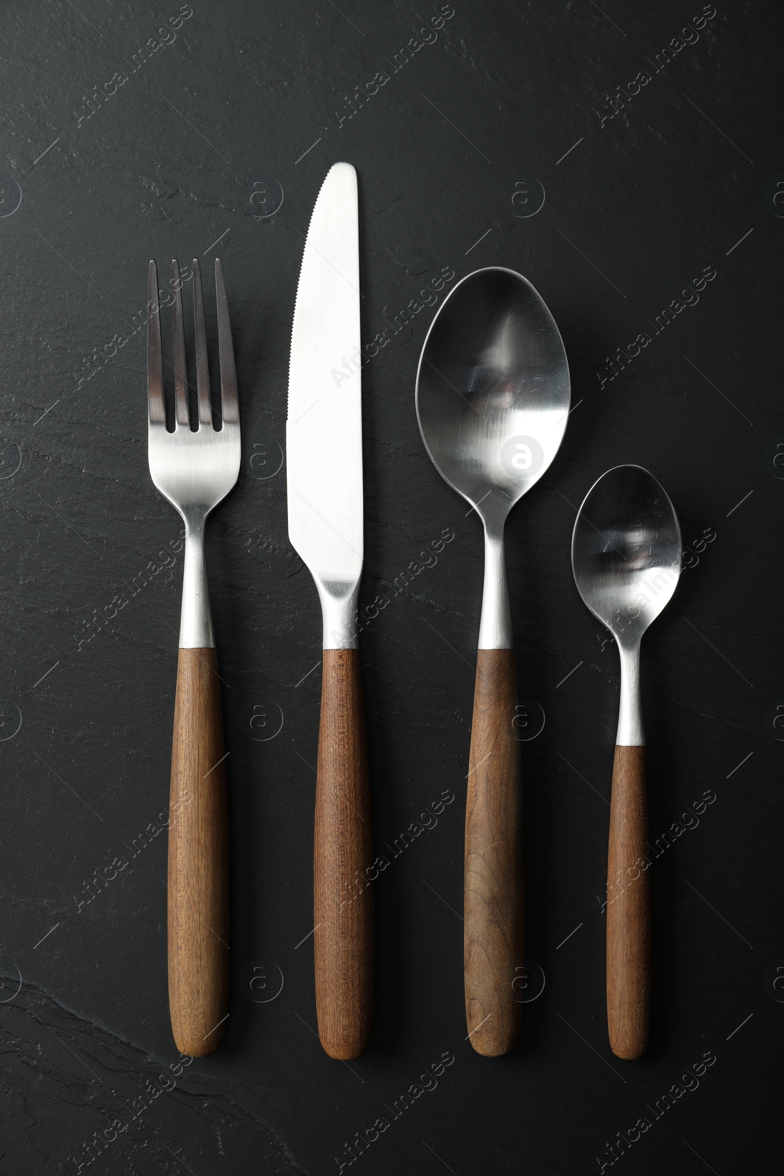 Photo of Stylish cutlery on black table, flat lay