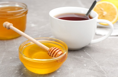 Photo of Tasty honey and tea on brown marble table, closeup