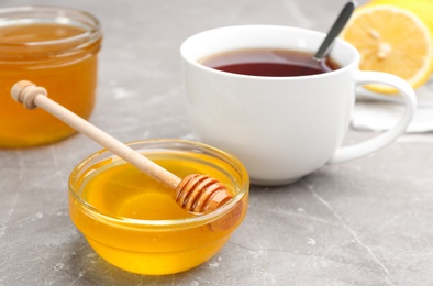 Tasty honey and tea on brown marble table, closeup