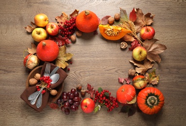 Photo of Frame made of autumn vegetables, fruits and cutlery on wooden background, flat lay with space for text. Happy Thanksgiving day