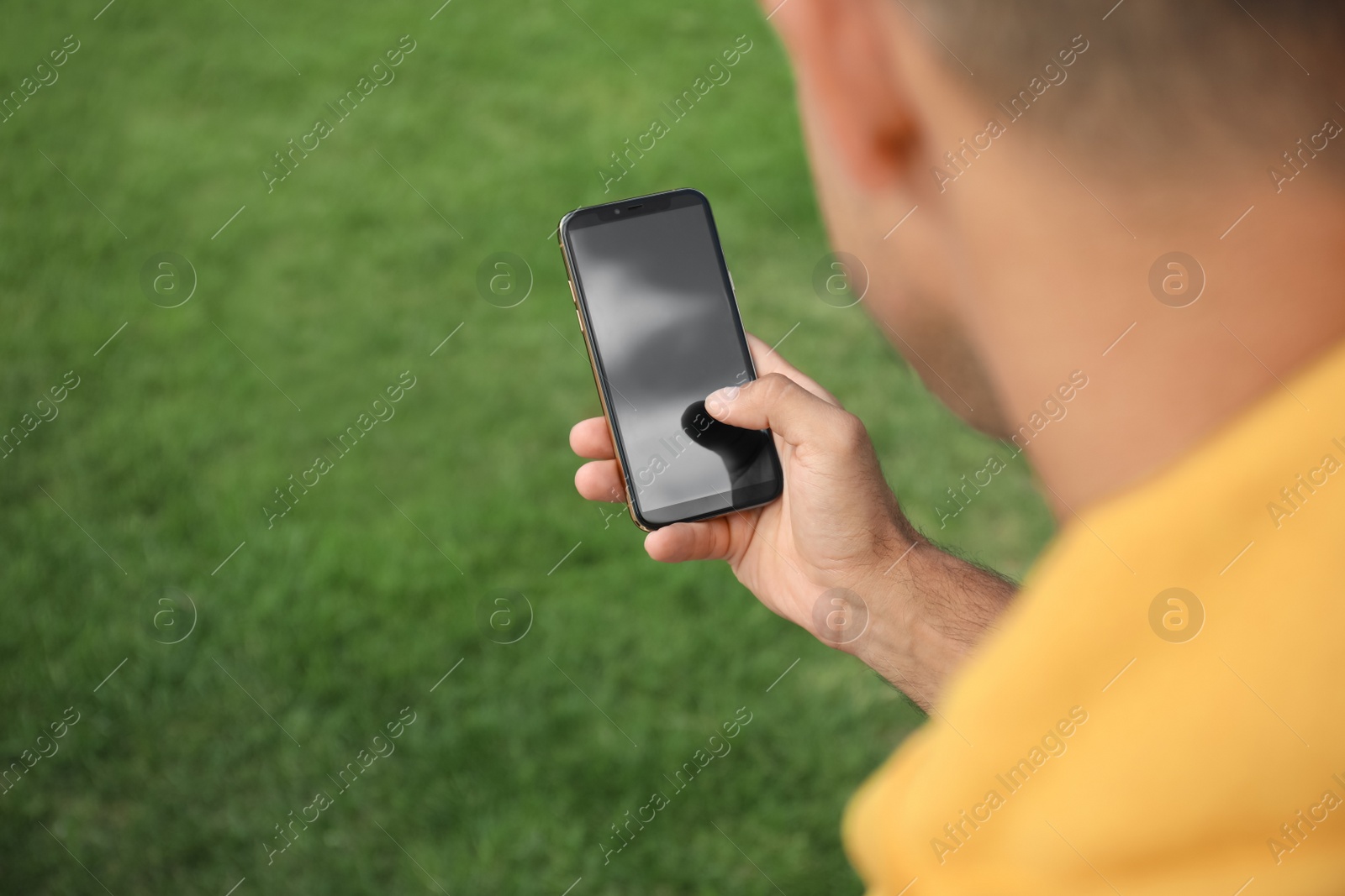 Photo of Man with smartphone in park on summer day, closeup