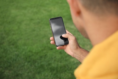 Man with smartphone in park on summer day, closeup