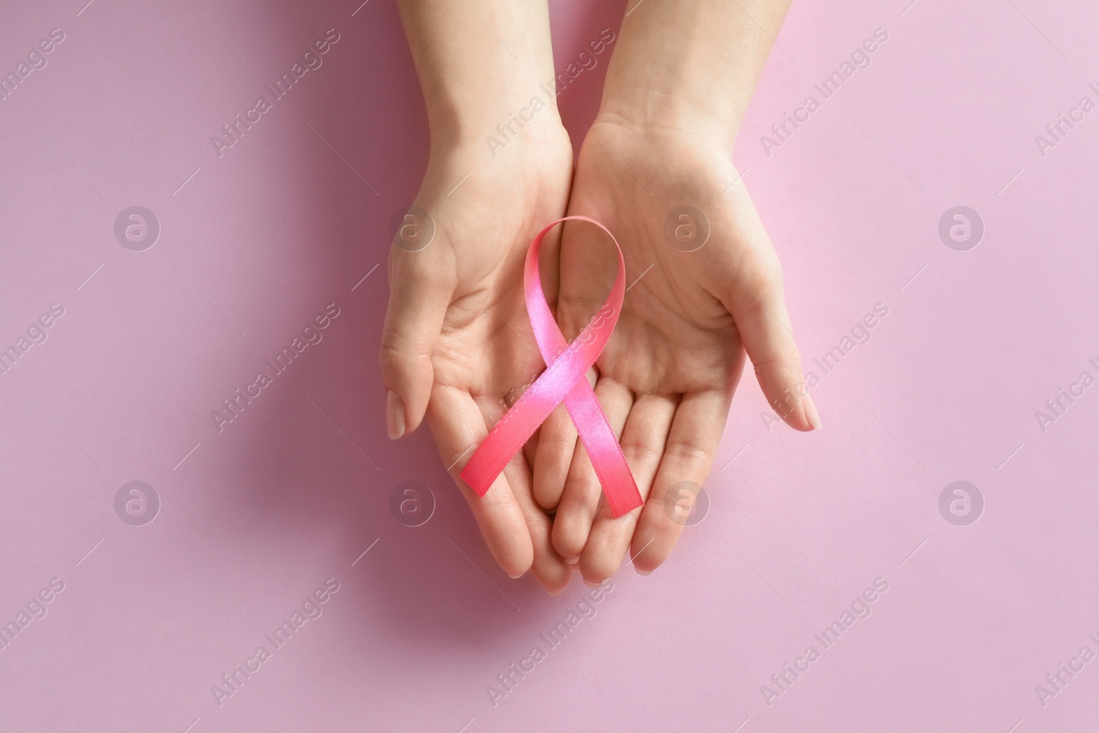 Photo of Woman holding pink ribbon on color background, top view. Breast cancer awareness