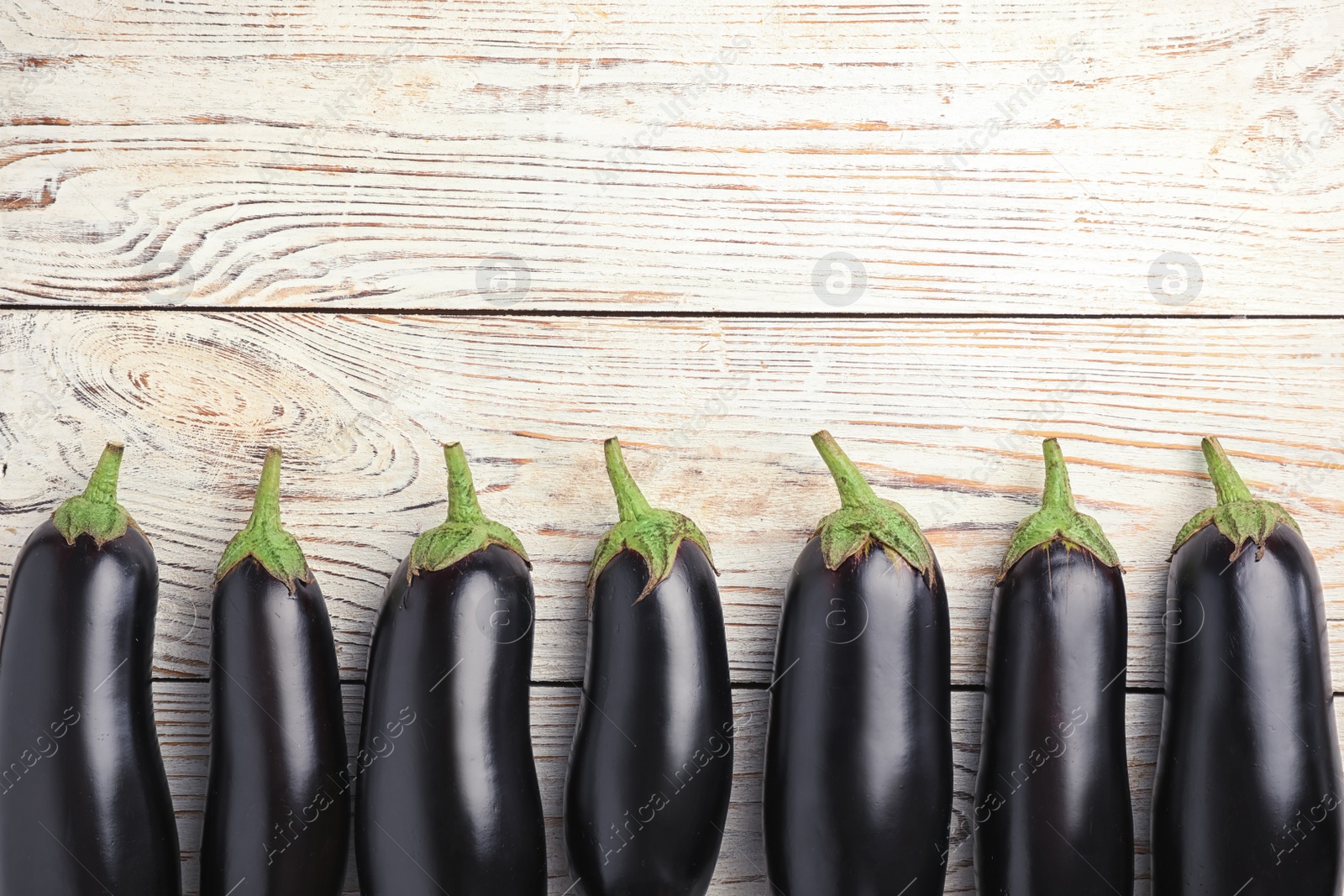 Photo of Raw ripe eggplants on wooden background, top view