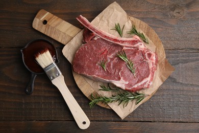 Photo of Raw meat, rosemary and marinade on wooden table, flat lay