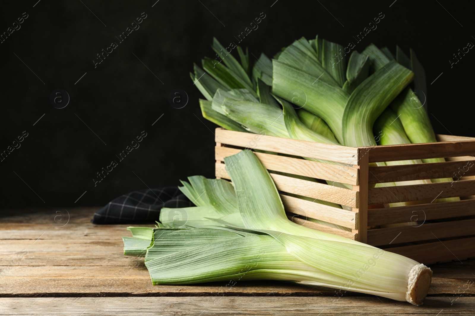 Photo of Fresh raw leeks on wooden table. Ripe onion