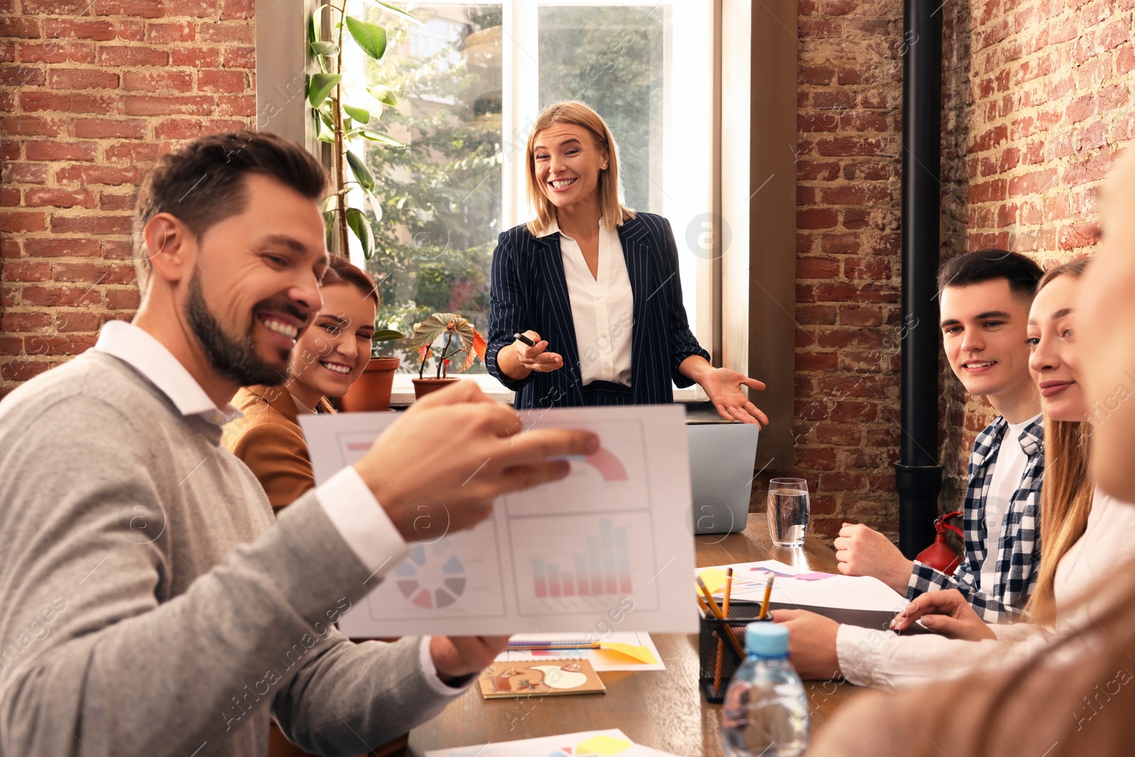 Photo of Businesswoman having meeting with her employees in office. Lady boss