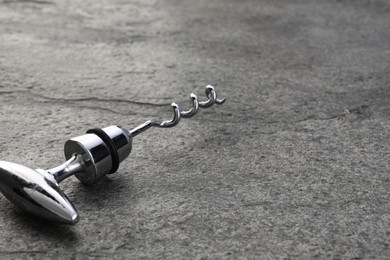 One metal corkscrew on grey textured table, closeup. Space for text