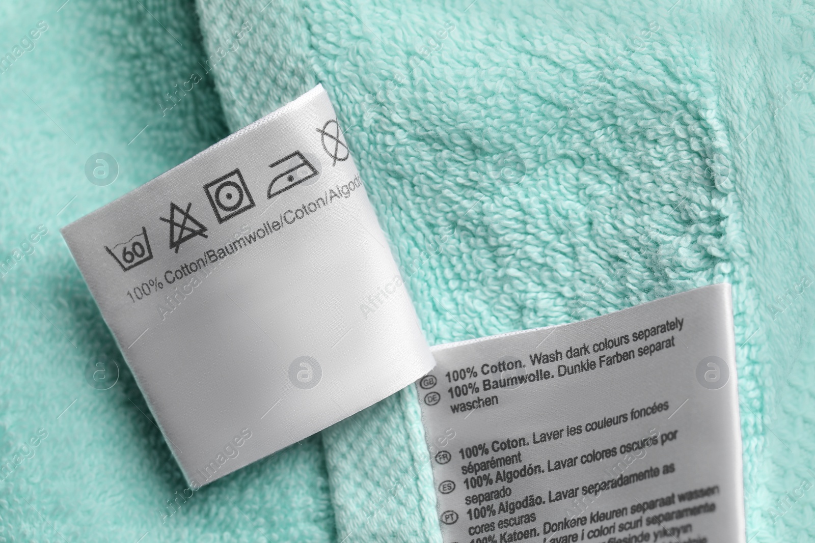Photo of Clothing labels on turquoise fluffy towel, closeup