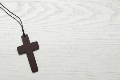 Photo of Wooden Christian cross on white table, top view. Space for text