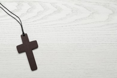 Wooden Christian cross on white table, top view. Space for text