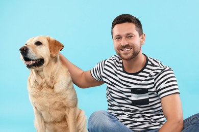 Photo of Man with adorable Labrador Retriever dog on light blue background. Lovely pet