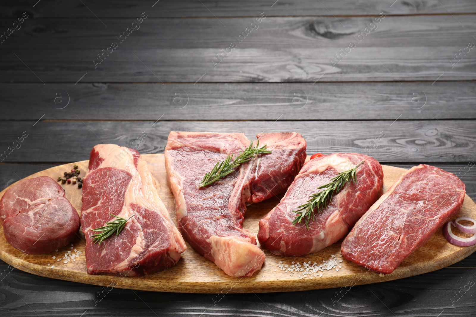 Photo of Pieces of raw beef meat on black wooden table