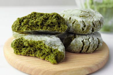 Photo of Board with stacked tasty matcha cookies on white table, closeup