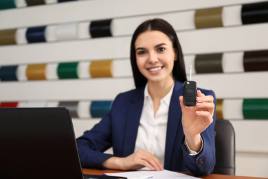 Photo of Saleswoman with car key at desk in office