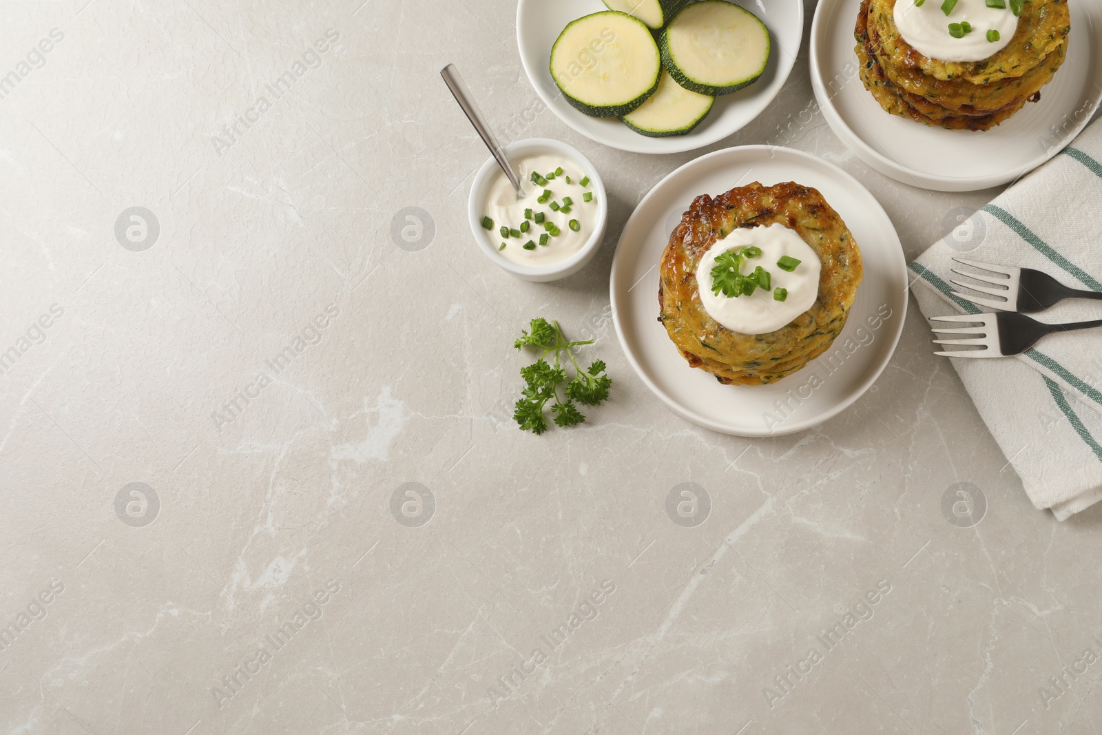 Photo of Delicious zucchini pancakes served on light grey table, flat lay. Space for text