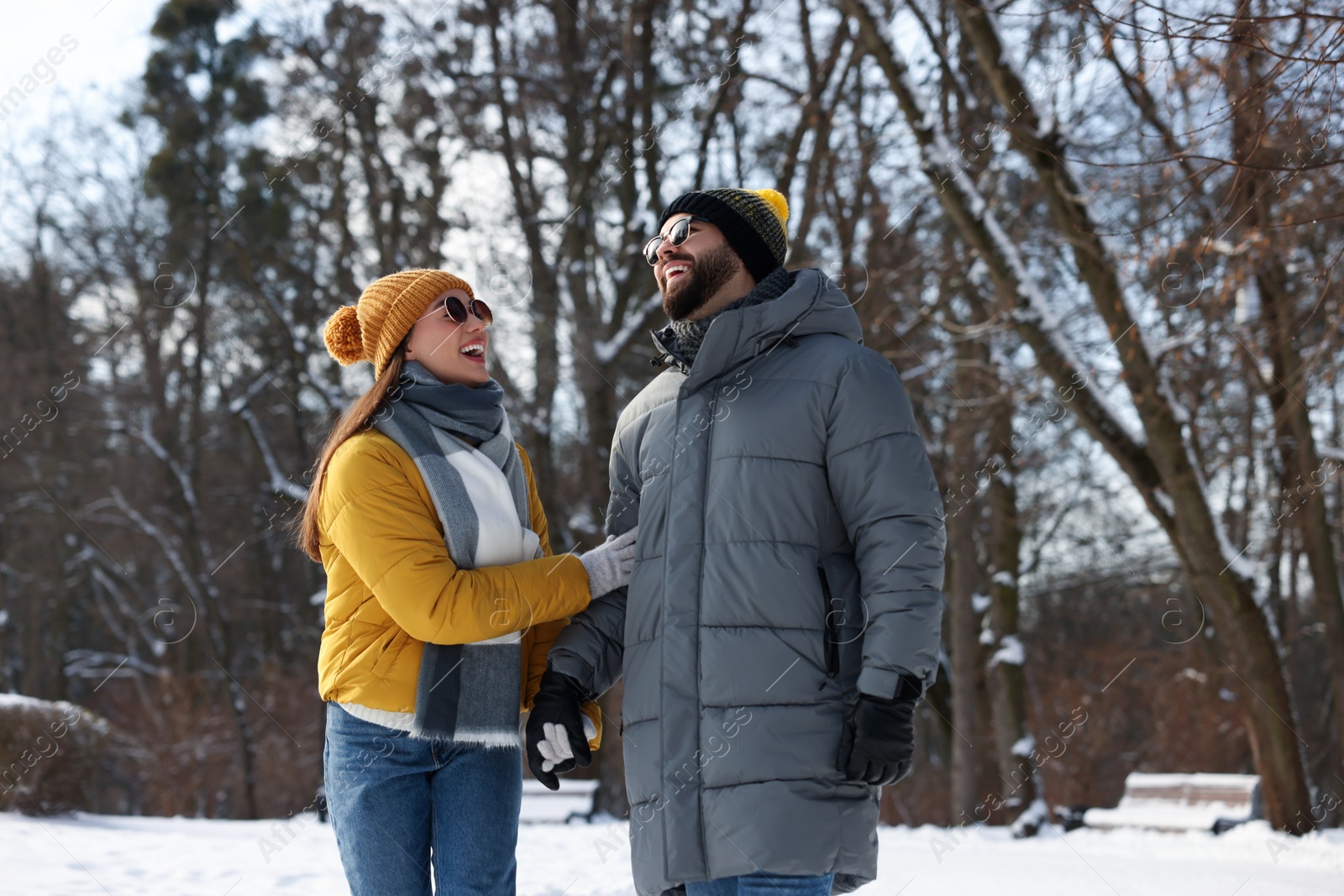 Photo of Beautiful happy couple walking in snowy park on winter day