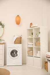 Photo of Modern washing machine near white wall in elegant bathroom