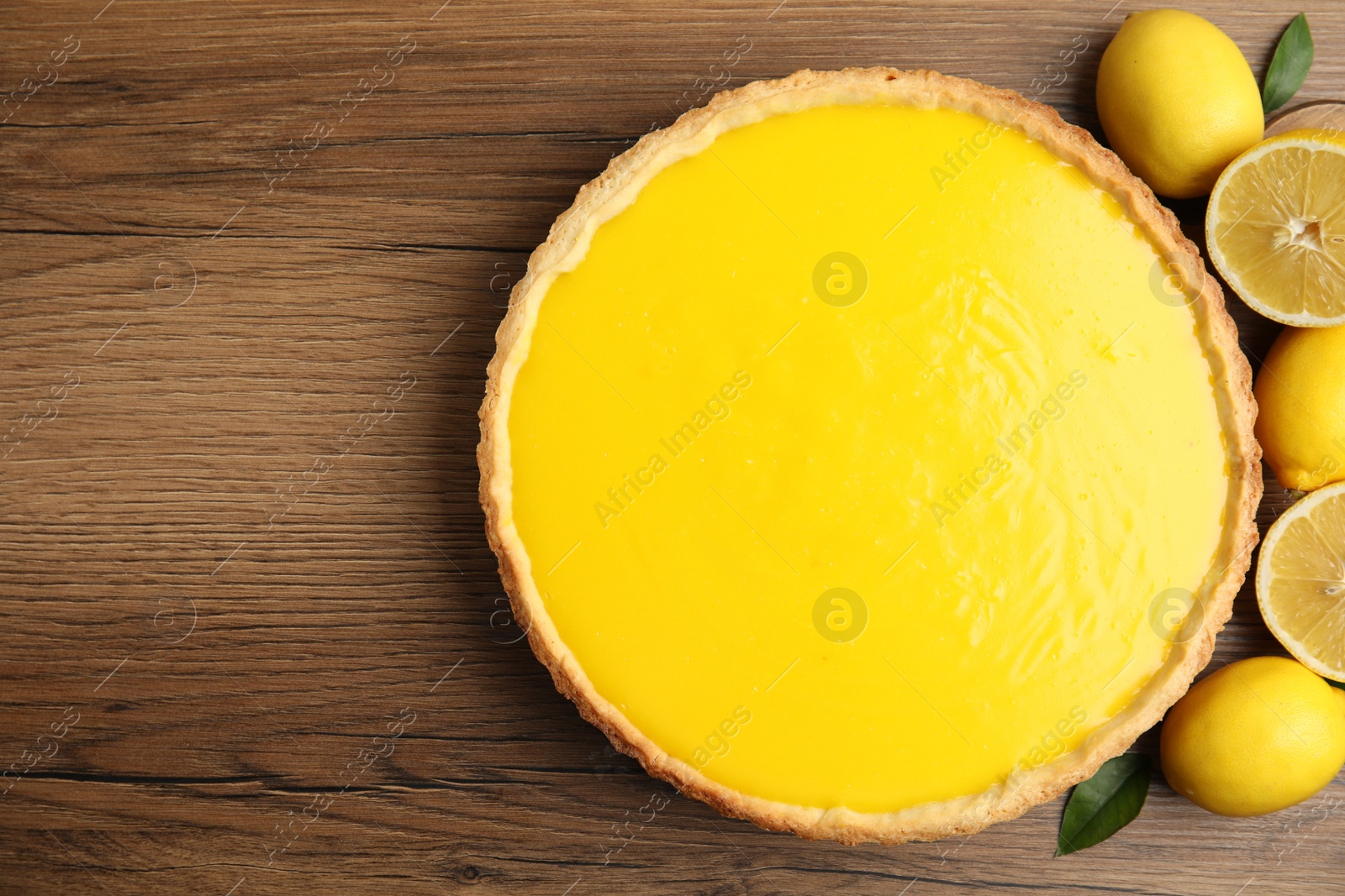 Photo of Delicious homemade lemon pie and fresh fruits on wooden table, flat lay. Space for text