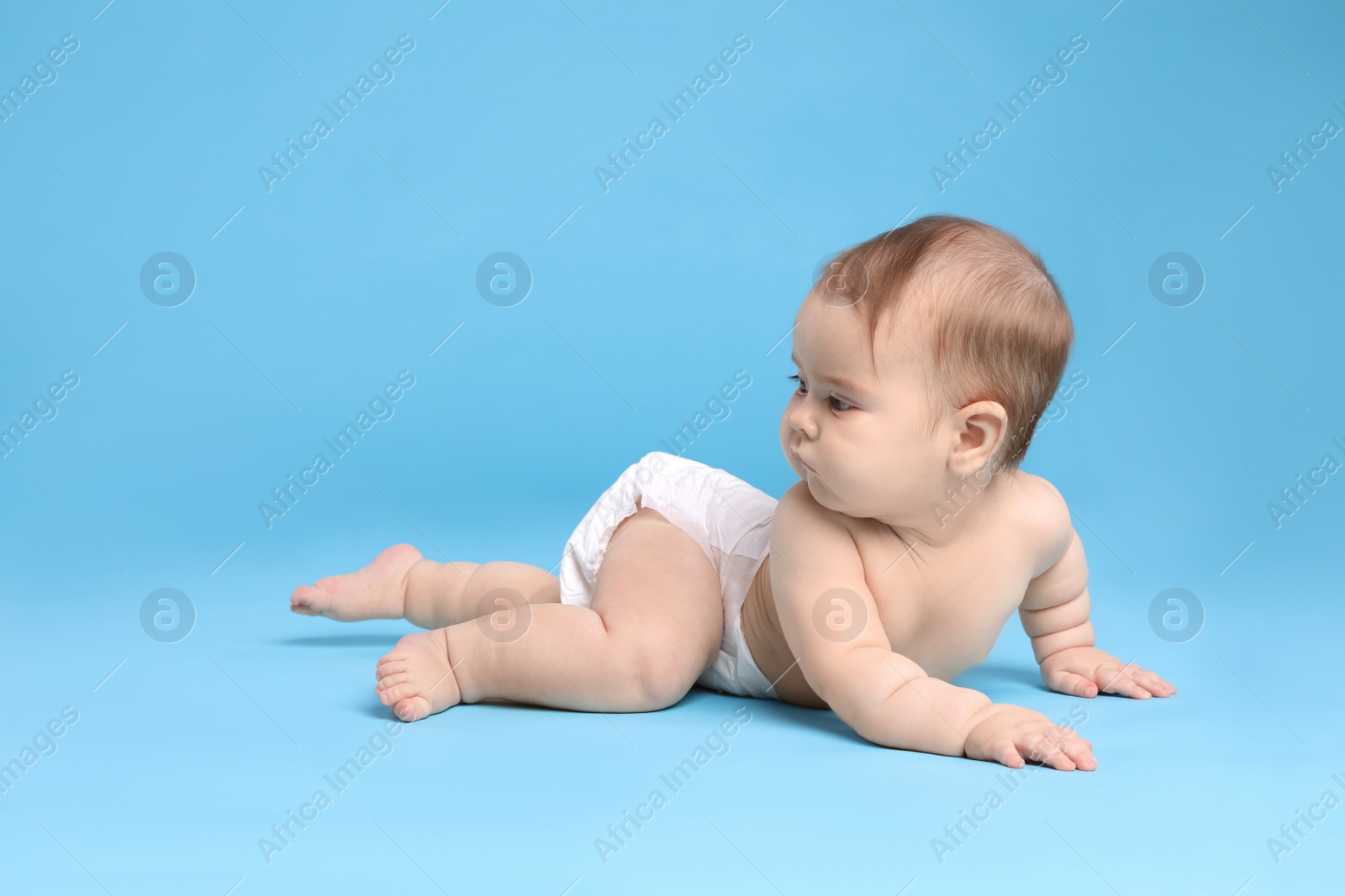 Photo of Cute little baby in diaper on light blue background. Space for text