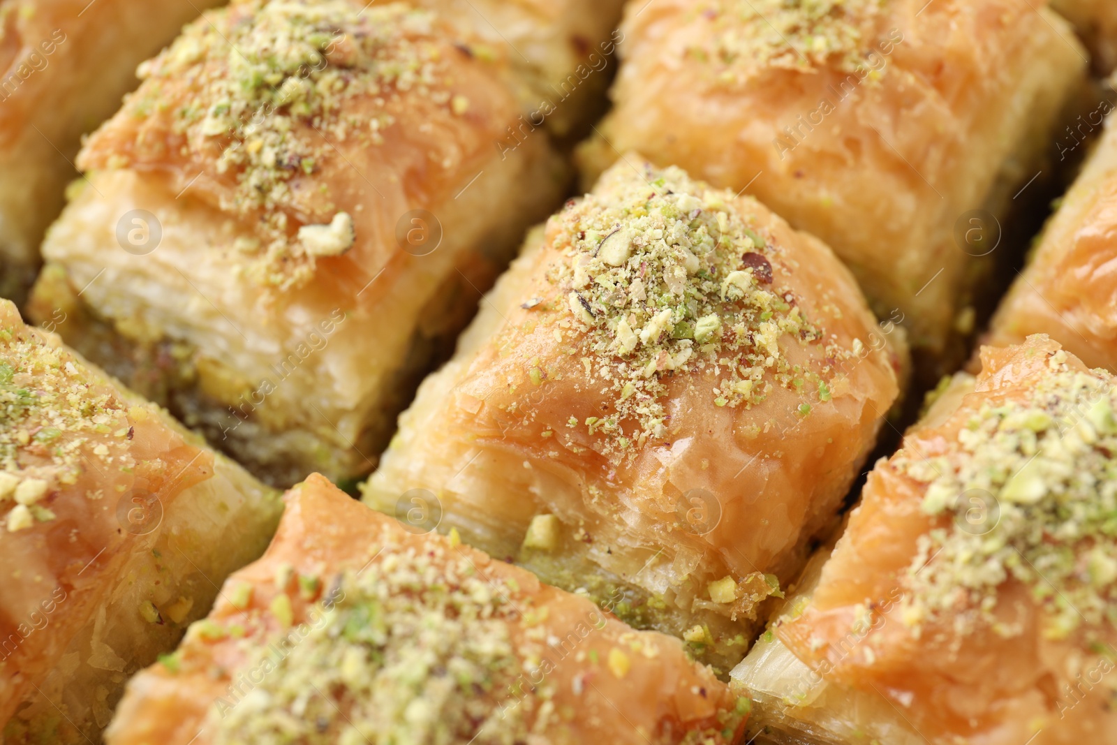 Photo of Delicious fresh baklava with chopped nuts as background, closeup. Eastern sweets