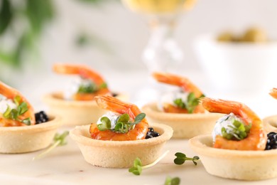 Delicious canapes with shrimps and black caviar on light table, closeup