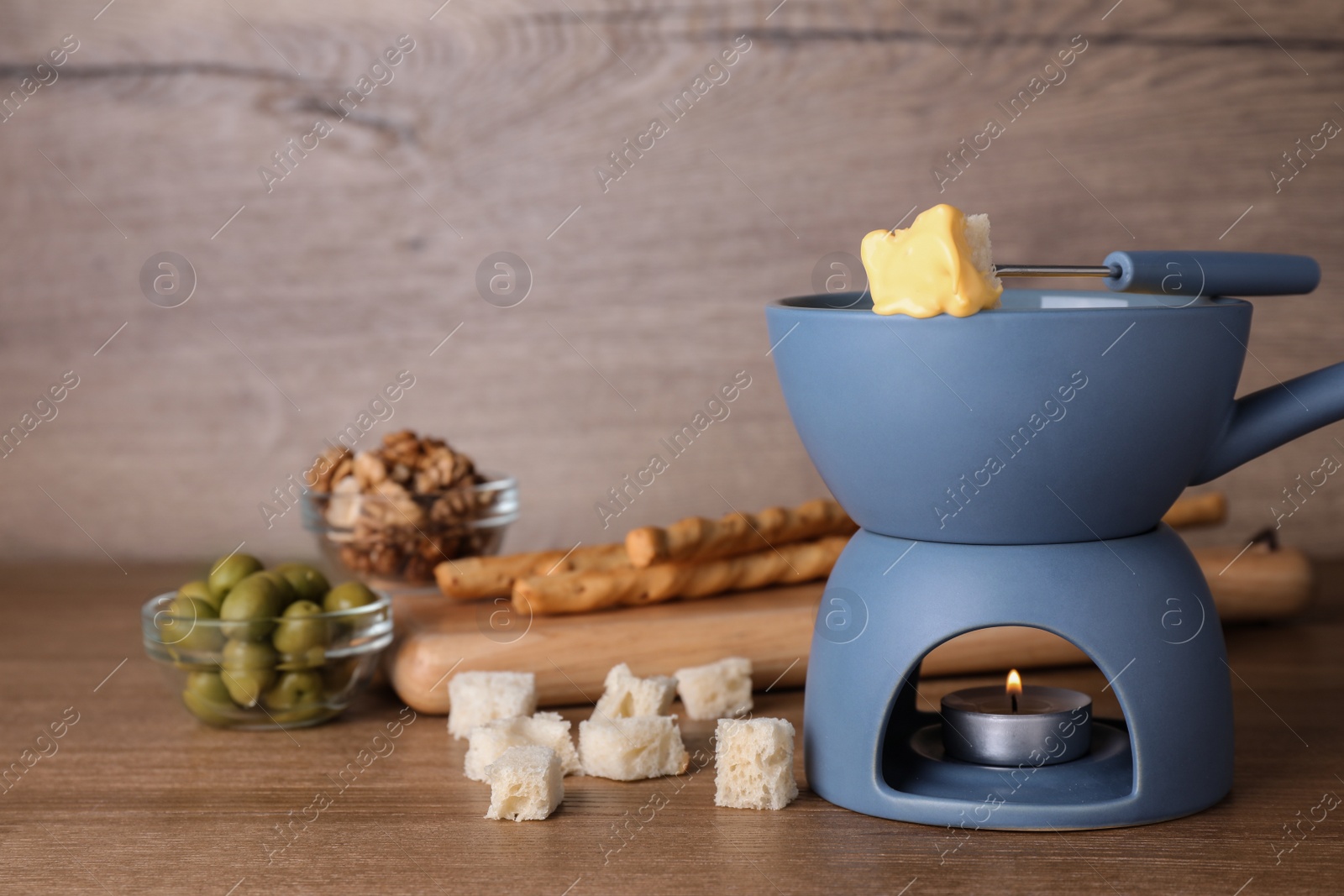 Photo of Pot of cheese fondue and products on wooden table, space for text