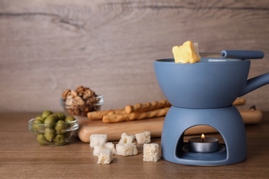 Pot of cheese fondue and products on wooden table, space for text