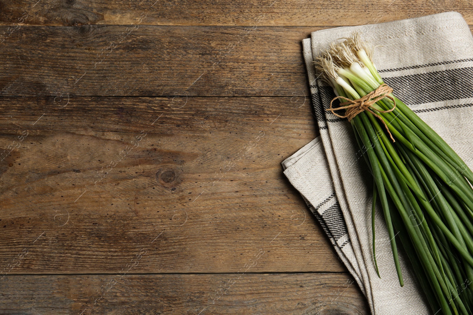 Photo of Fresh green spring onions on wooden table, flat lay. Space for text