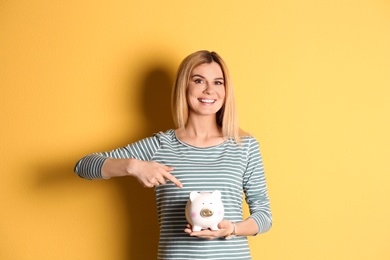 Woman with piggy bank on color background