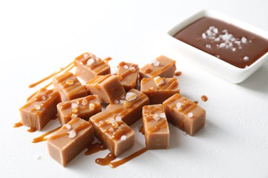 Tasty candies, caramel sauce and salt on white table