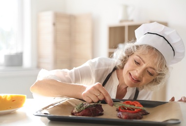 Photo of Professional female chef preparing meat on table in kitchen