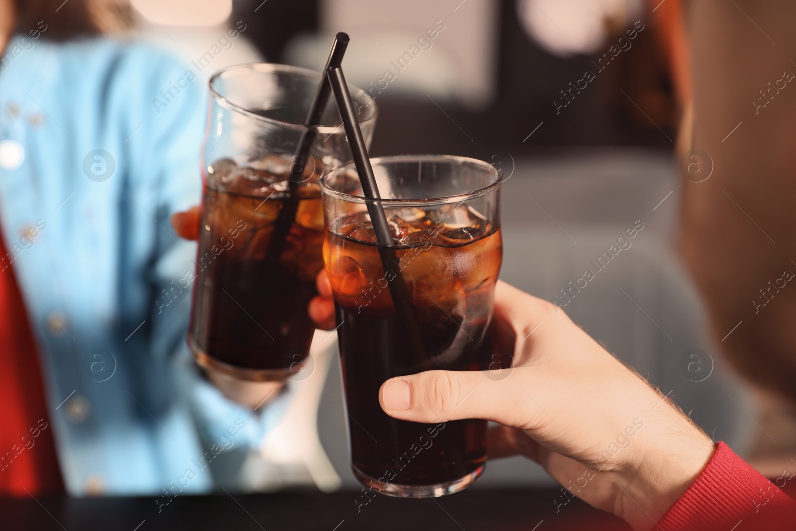 Photo of Young couple with glasses of cola at table indoors, closeup