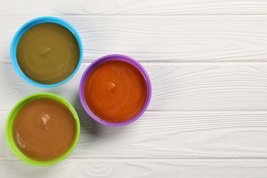 Photo of Baby food. Different purees in bowls on white wooden table, flat lay. Space for text