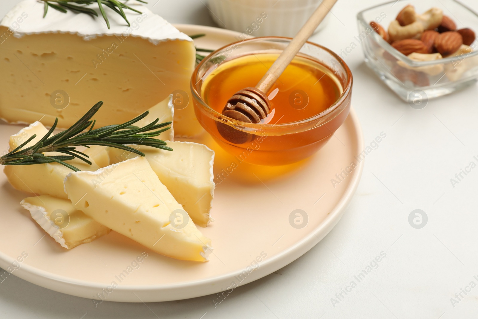 Photo of Tasty Camembert cheese with rosemary and honey on white table, closeup