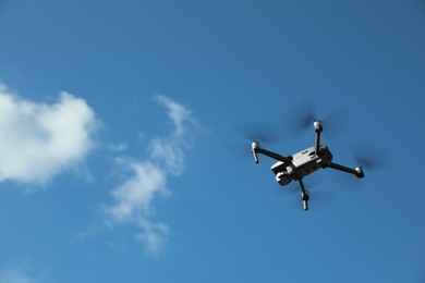 Modern drone with camera flying in sky on sunny day