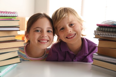 Photo of Little boy and girl at table with books. Doing homework