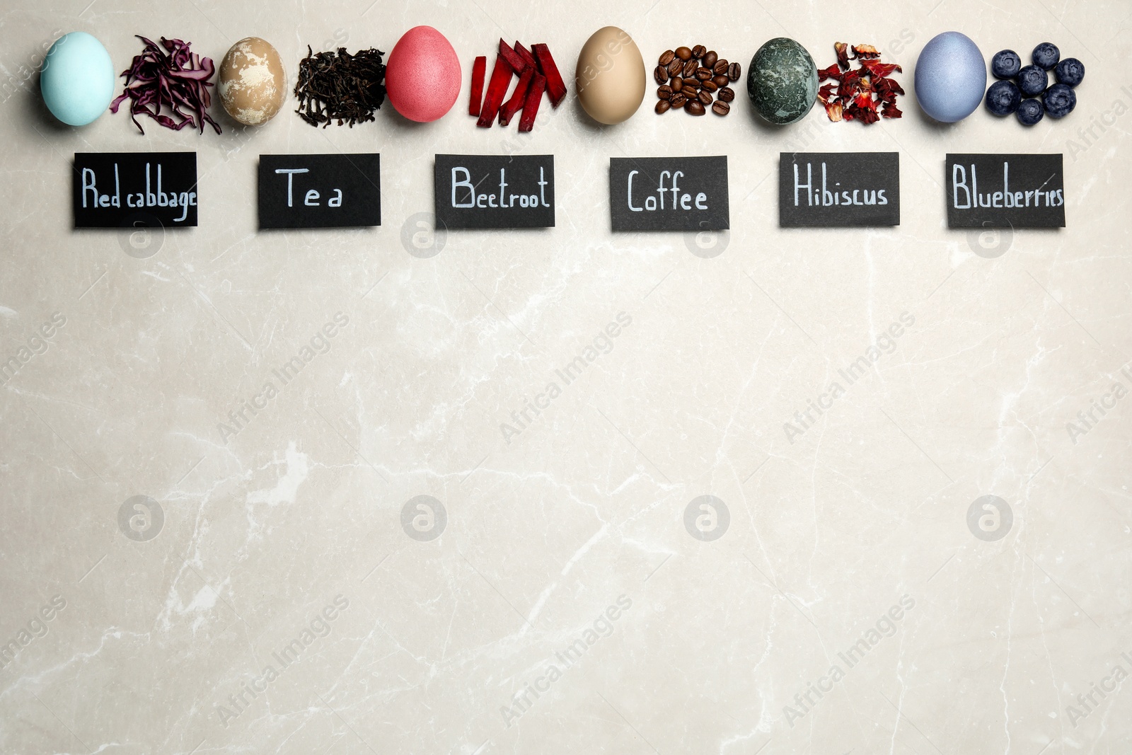 Photo of Easter eggs painted with natural organic dyes and labels on light grey table, flat lay. Red cabbage, tea, beetroot, coffee beans, hibiscus, blueberries used for coloring. Space for text
