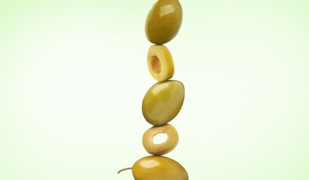 Image of Cut and whole olives on light green gradient background