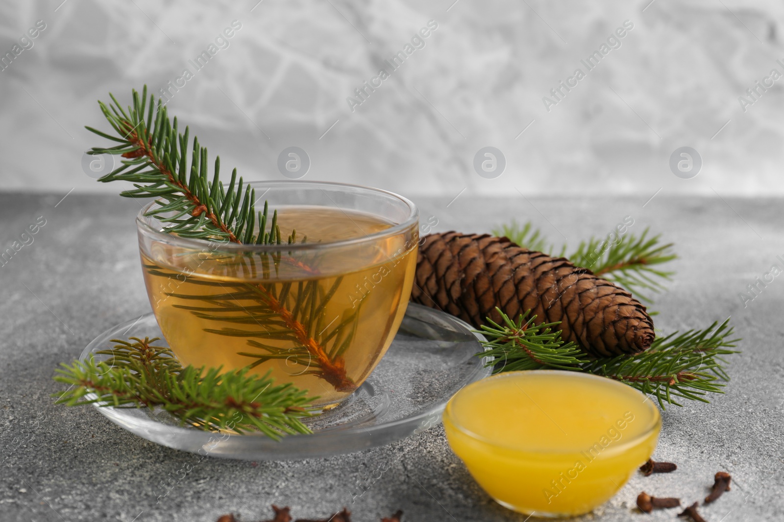 Photo of Cup with delicious immunity boosting tea, fir and ingredients on grey table