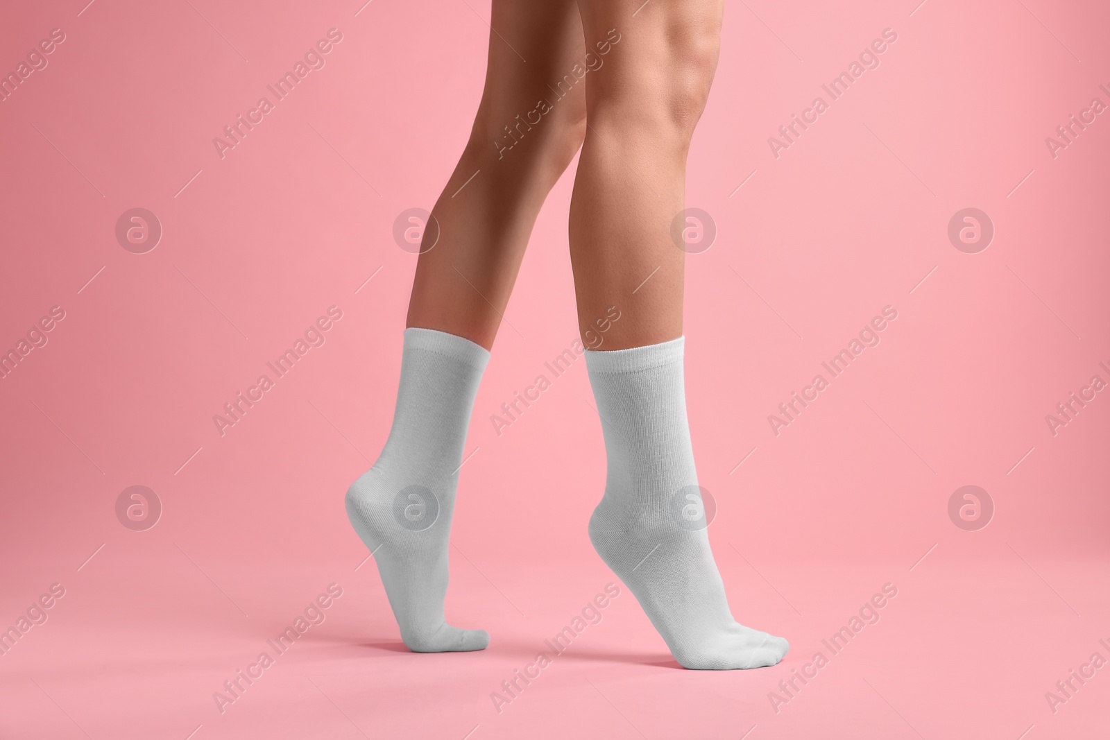 Photo of Woman in stylish white socks on pink background, closeup